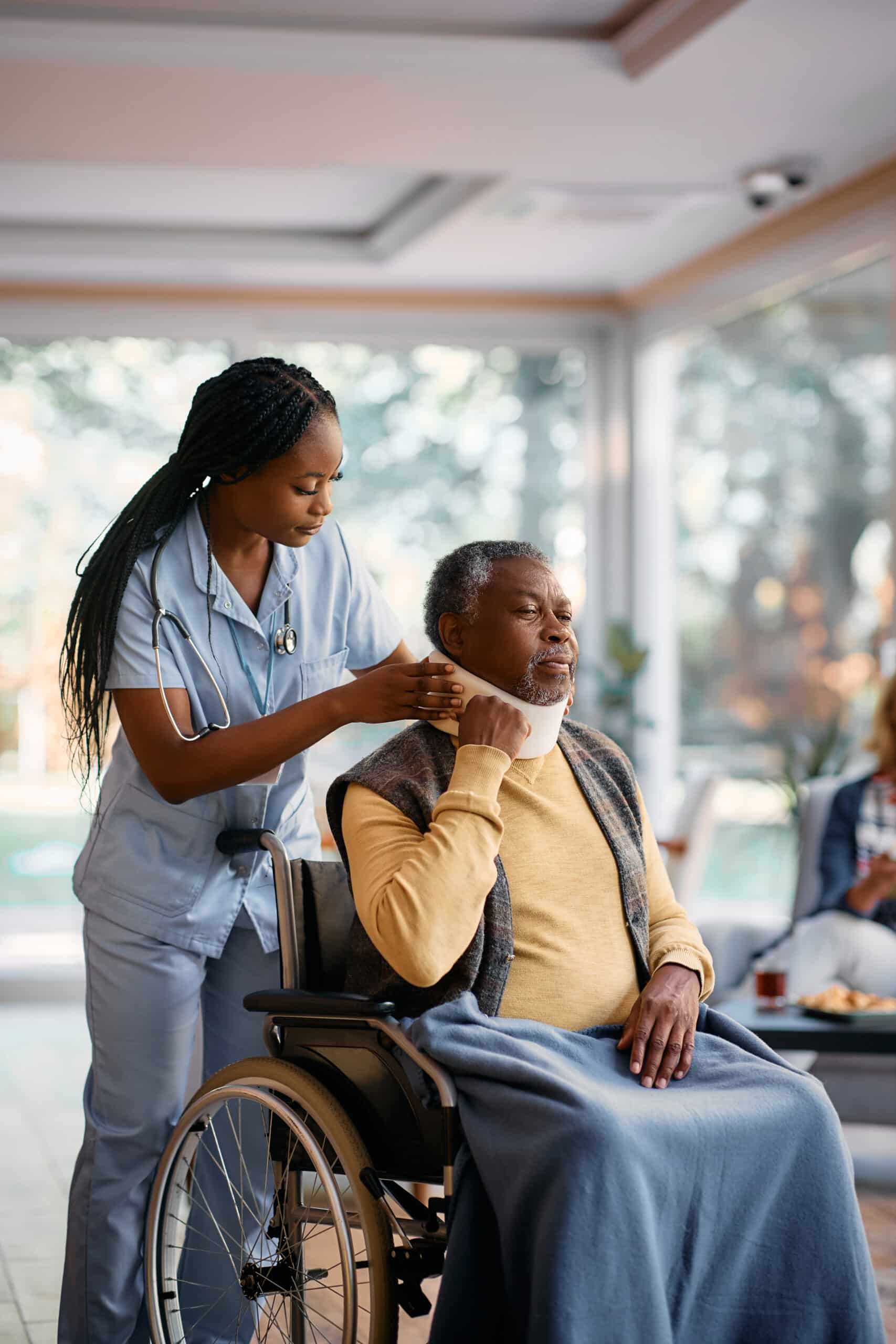 young black nurse adjusting neck collar to elderly scaled